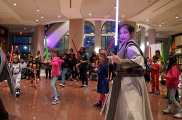 children holding lightsabers and listening to a demonstration at the Bullock Museum