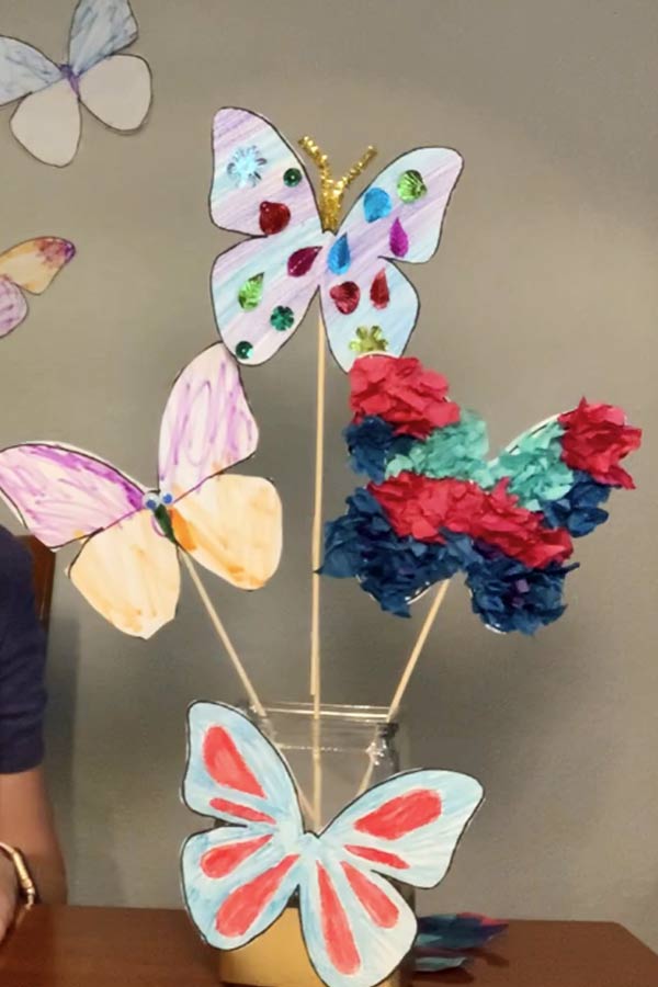 Three colorful paper butterflies on sticks in a vase
