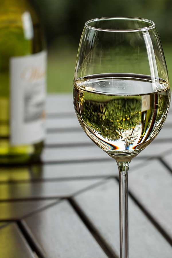 Glass of white wine on a wooden table outdoors