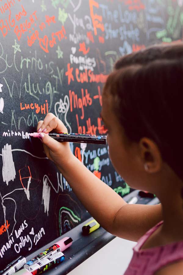 Close up of child drawing on a black chalkboard