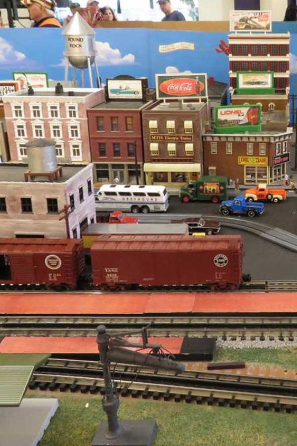 a model train set of two red train cars going through a city