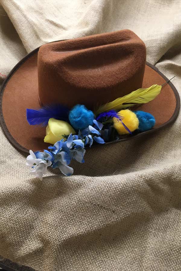 a brown cowboy hat decorated with yellow and blue flowers and feathers