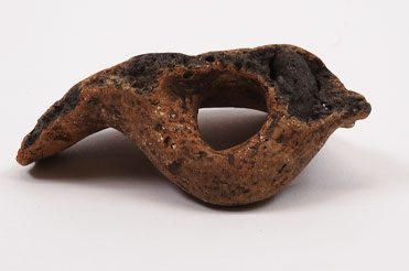 aged red-orange pottery piece with a hole in the center on a white background