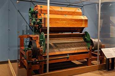 wooden and green Continental cleaner feeder cotton gin on display in the Bullock Museum