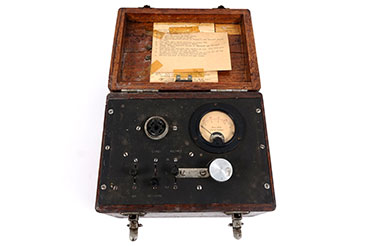 A small black, box-shaped device with a gauge on the top with brown detail