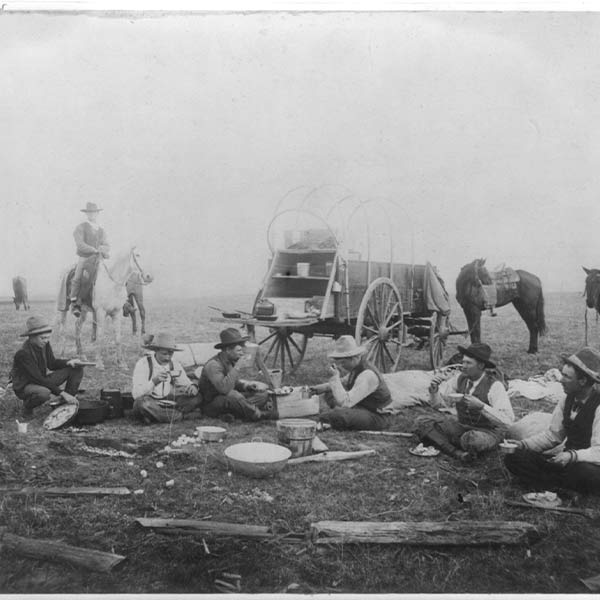 As the new system of ranching took off, cowboys had to spend days or even weeks on the open range or cattle trail and needed mobile kitchens that could travel with them. The solution was the chuck wagon - a wagon outfitted with a "chuck box" containing drawers and shelves for storing supplies and could fold out into a work surface.  This photograph shows a group of cowboys taking a break for a meal on the range, their chuck wagon behind them.  Image courtesy Library of Congress Prints and Photographs Division Washington, D.C.