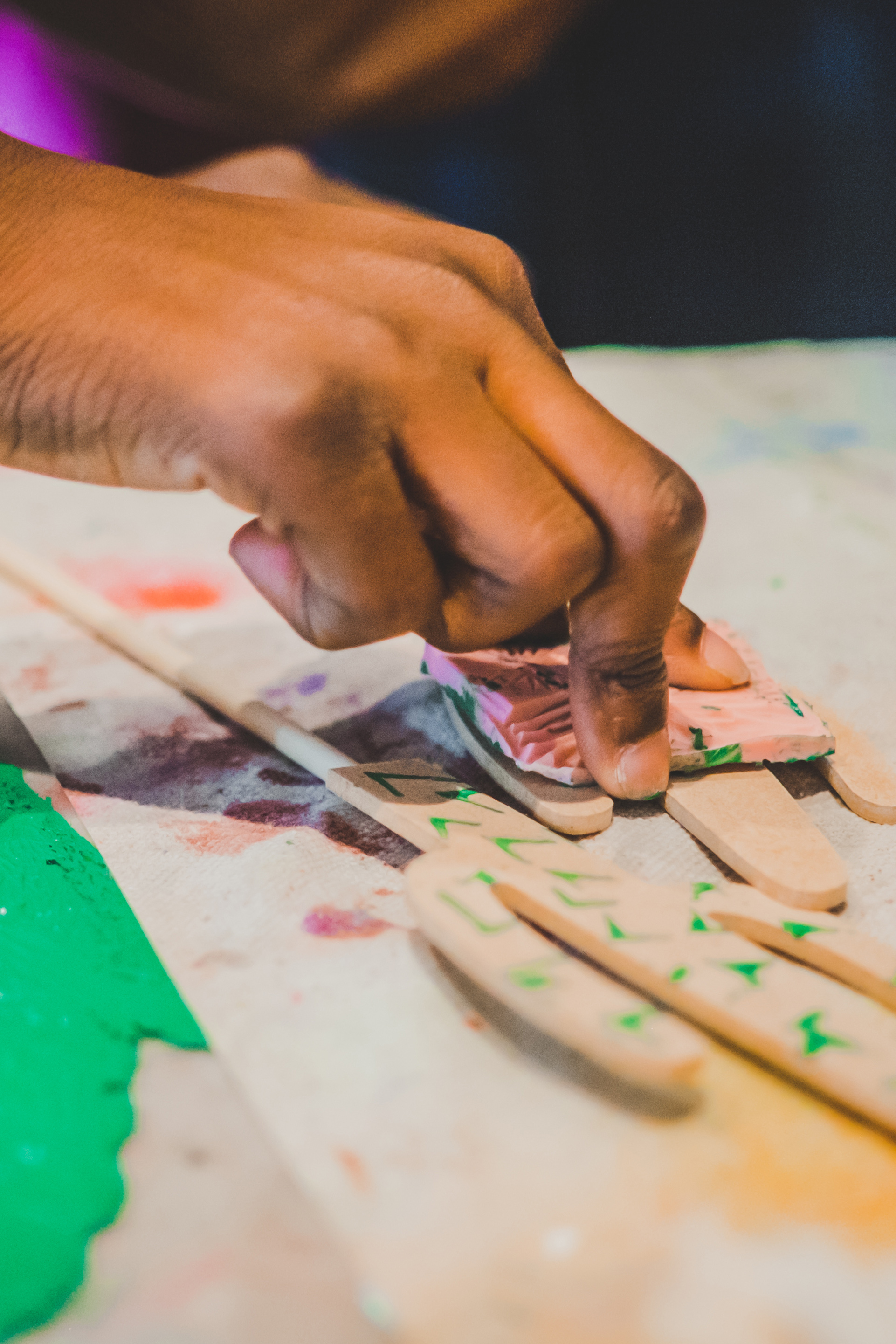 Person's hand putting a stamp onto wooden craft sticks