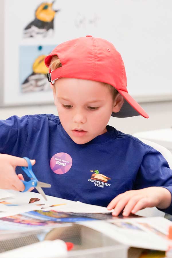 a young kid with a red baseball cap holding a pair of scissors