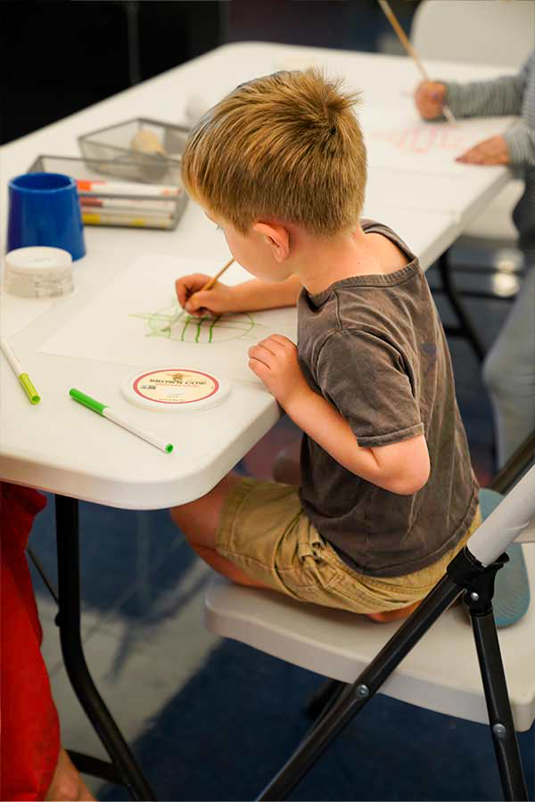 a boy sitting at a table drawing in the Bullock Museum
