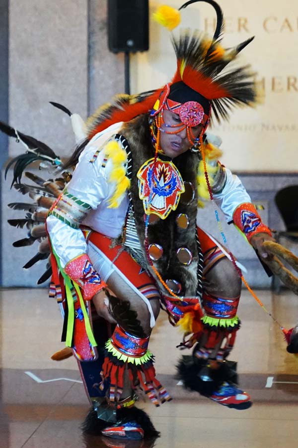 Man dancing with one foot in the air, wearing traditional Native American clothing