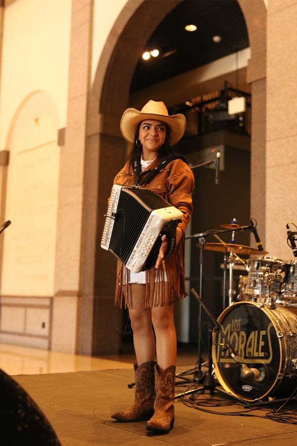 woman wearing a cowboy hat playing the accordion in the Bullock Museum