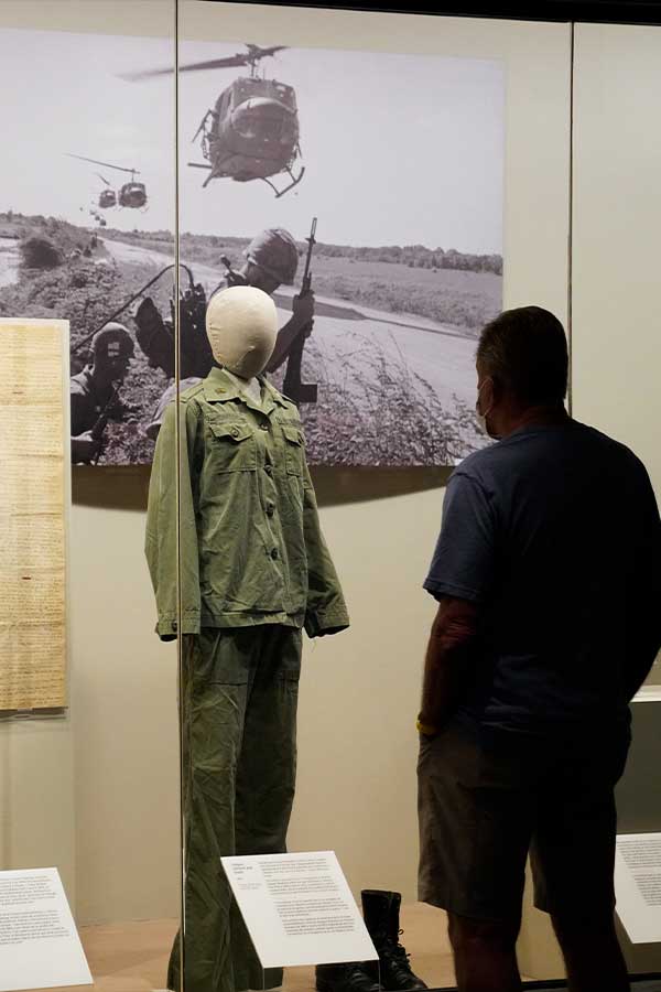 man standing in front of a Vietnam War veteran's uniform on display in the Bullock Museum