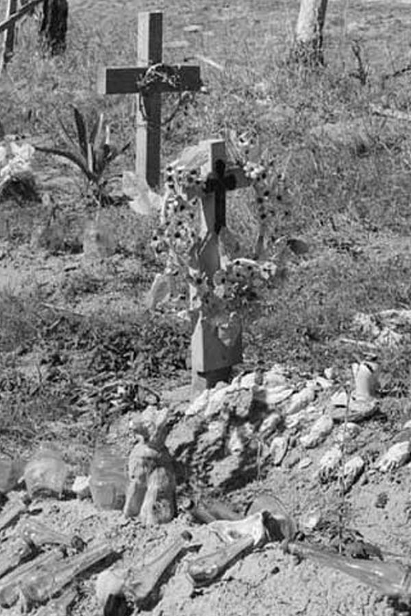 A black and white photo of a cemetery with decorated crosses.