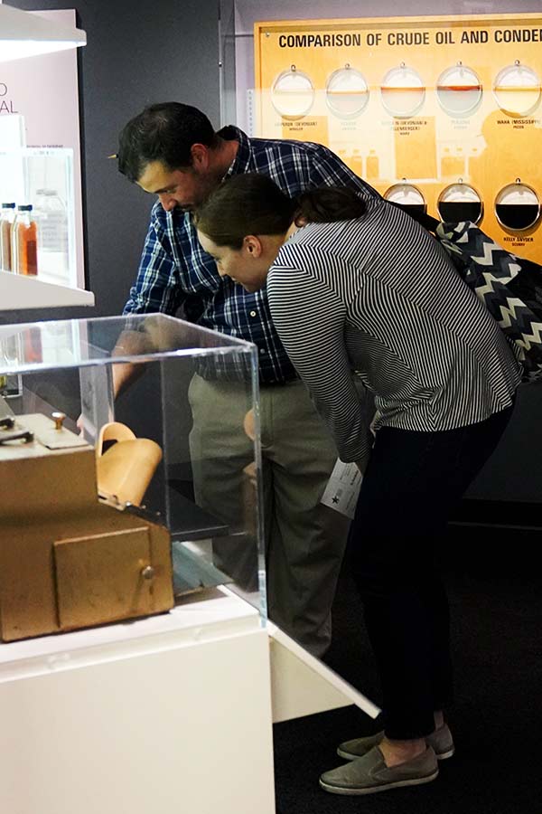 two adults bending down to get a closer look at artifacts in the Oil and Gas exhibit at the Bullock Museum