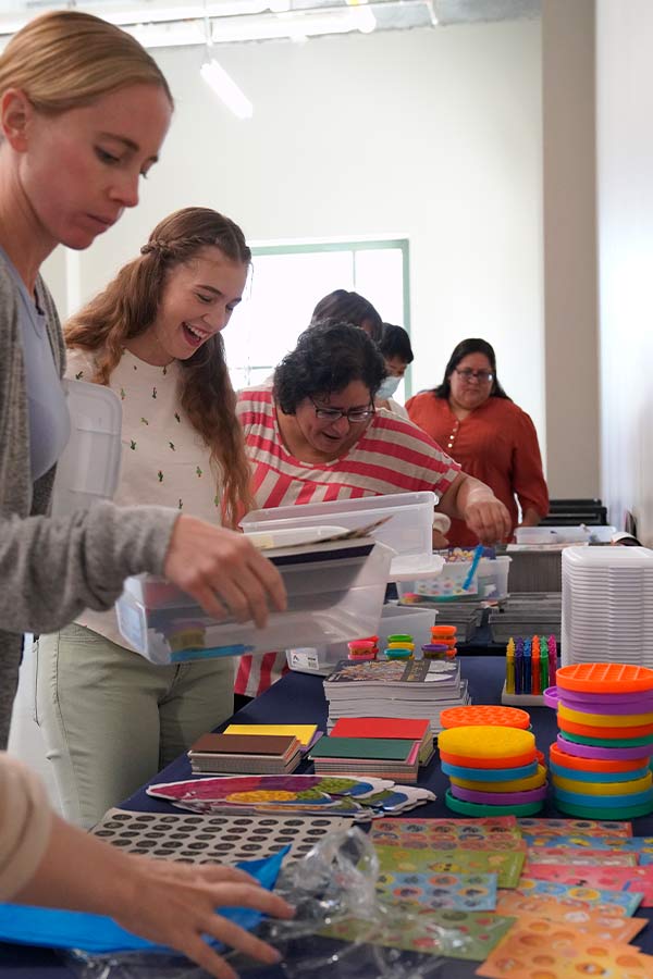 two teachers smiling and gathering craft items for an activity