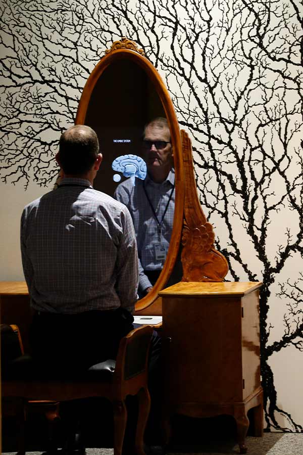 man sitting looking at an oval screen with an illustration of a brain