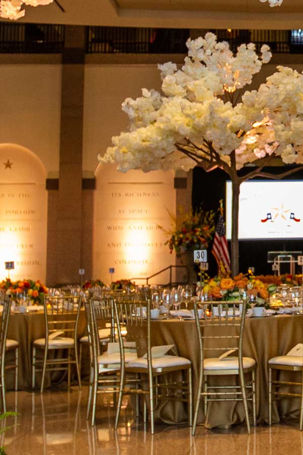 tables with flora centerpieces and chairs set up for an evening event