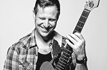 Portrait of musician Guy Forsyth with guitar