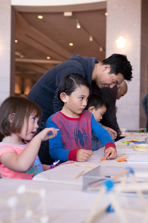 family at a table doing a craft at the Bullock Museum, one child is wearing a Spider Man shirt