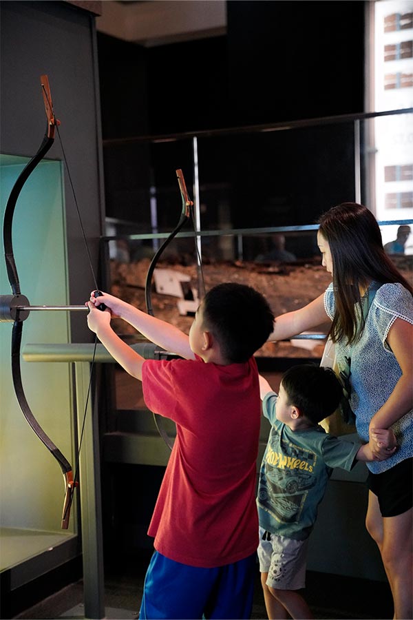 a family with two children pulling an interactive bow in the Bullock Museum