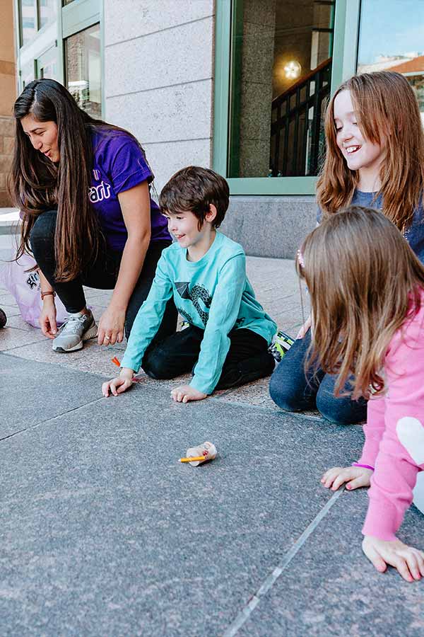 an adult and three adolescents doing an outdoor activity on the Bullock Museum plaza