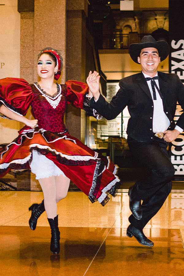 a man and a woman in traditional Mexican dress doing a folklorico dance