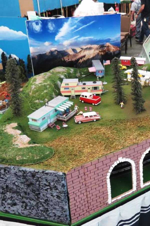 model train set up with rolling hills and a small building set against a blue sky