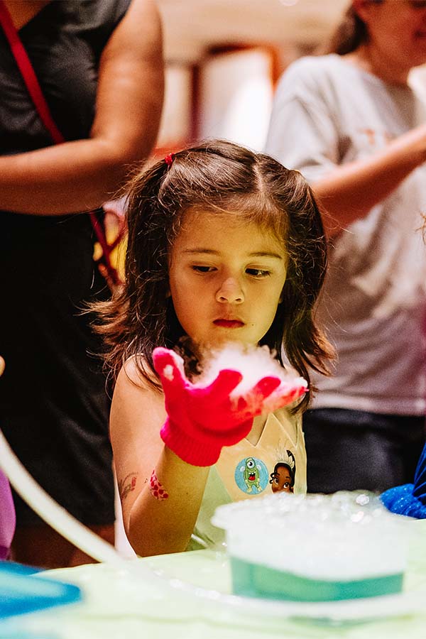 a young girl holding a smoking ball of dry ice in her gloved hand