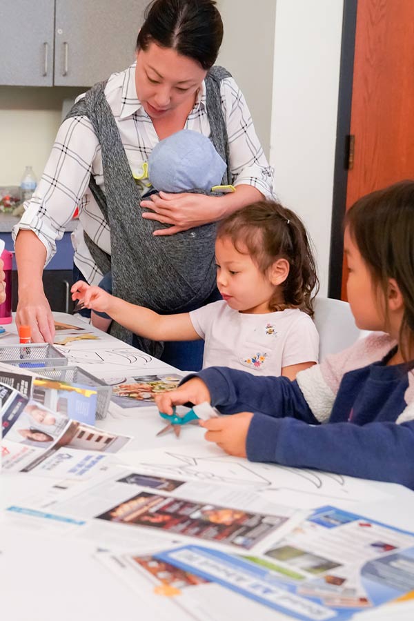 an adult and two little kids doing a craft activity in the Bullock Museum classrooms