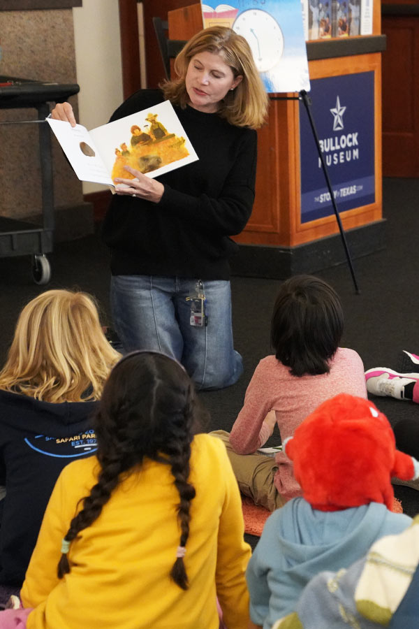 An adult reading a story to a group of children at the Bullock Museum.