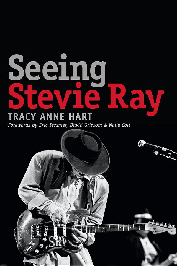 book cover of "Seeing Stevie Ray" with a black and white photo of Stevie Ray Vaughn playing a guitar on a black background