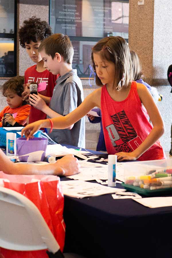 Group of children standing at a table with markers and other crafts at the Bullock Museum