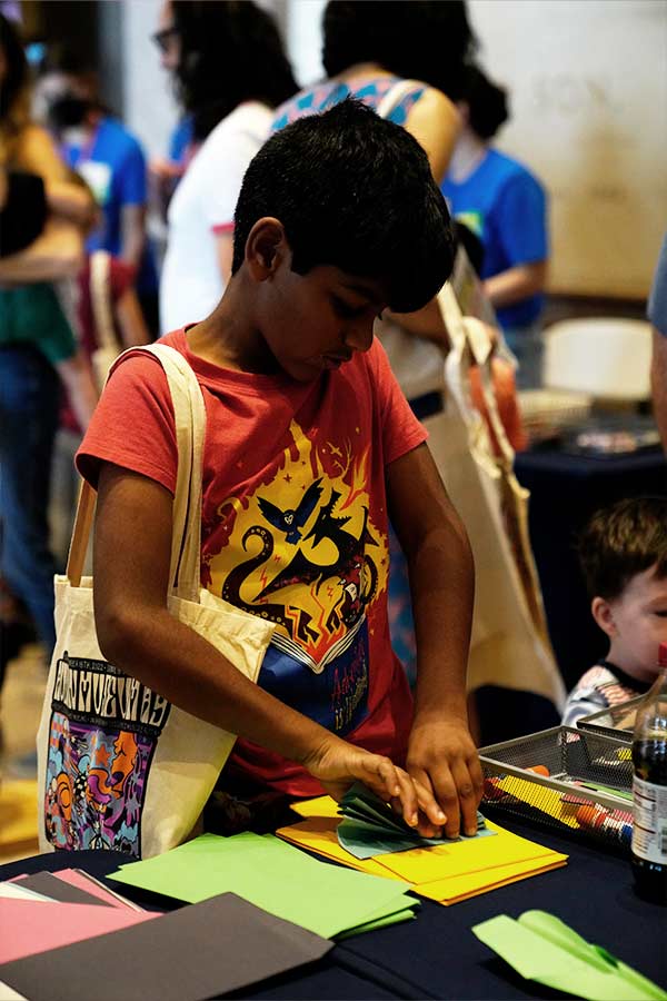 an adolescent standing at a table doing a paper craft in the Bullock Museum