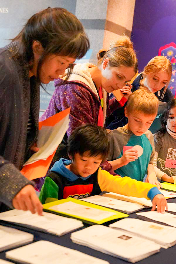 kids and adults gathered at a table picking up activity guides