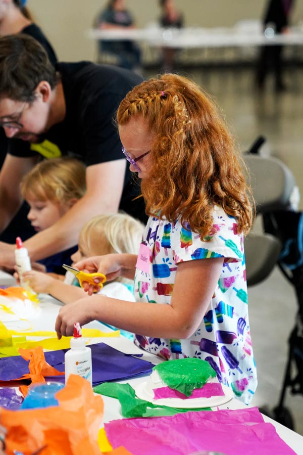 a young girl holding a pair of scissors doing a craft activity