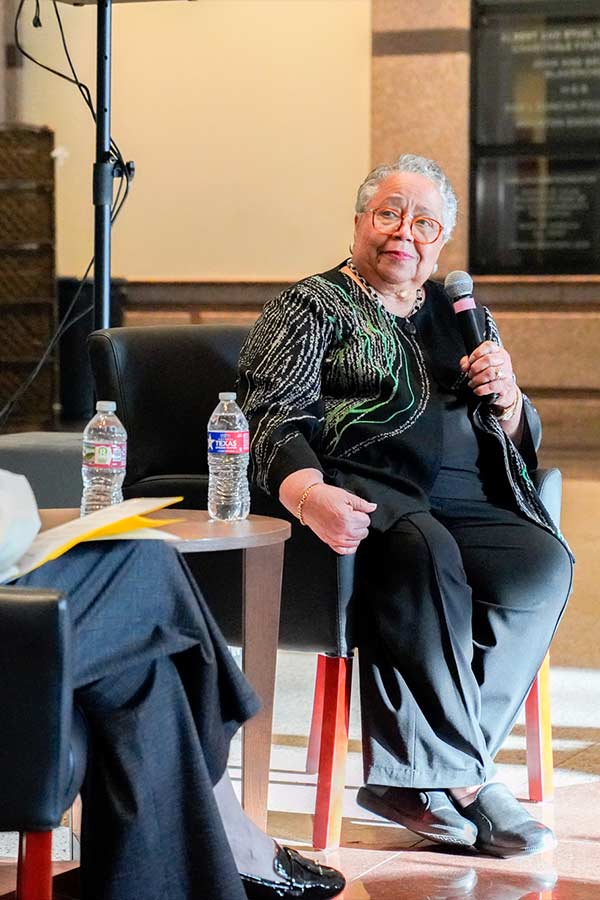 Harriet Kelley sitting in a chair holding a microphone in the Bullock Museum Grand Lobby