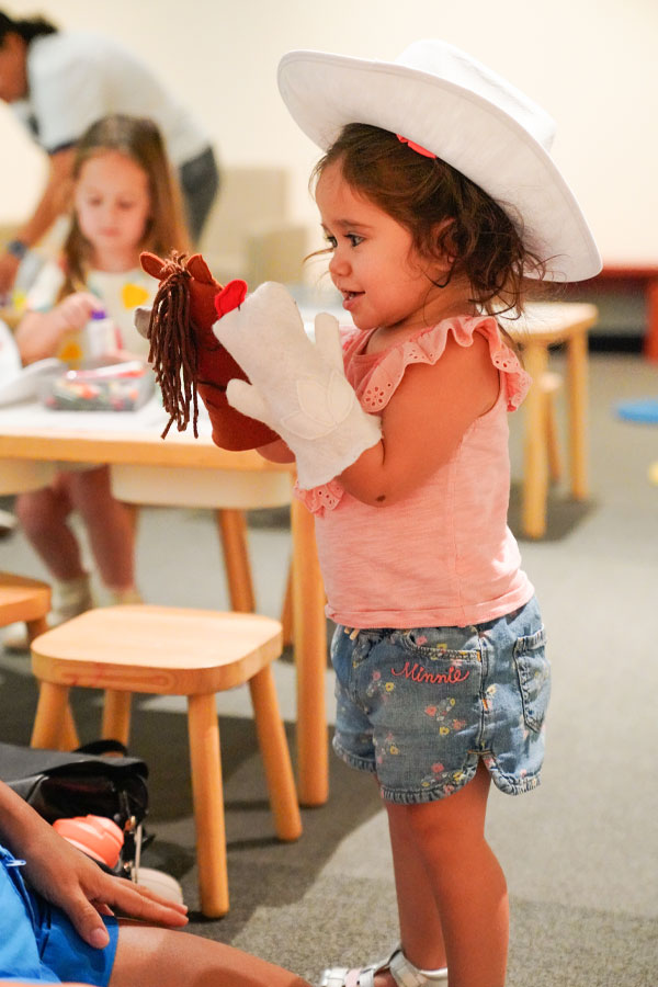 A child wearing a cowboy hat in a playroom at the Bullock Museum.