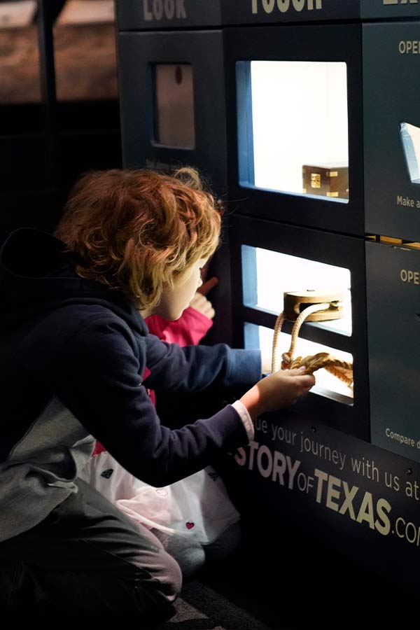 a young boy looking into an interactive discovery cart drawer in the Bullock Museum