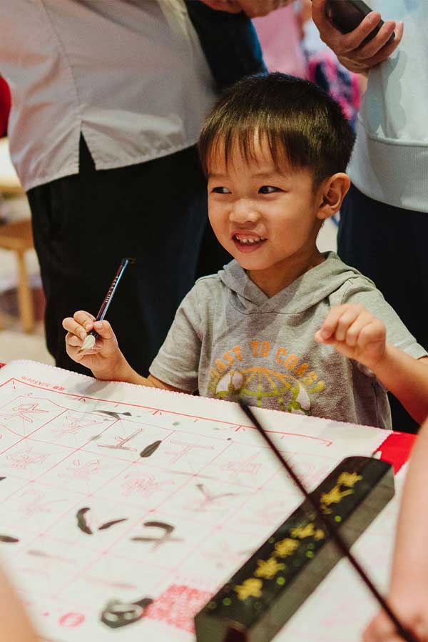 a young boy holding a paint brush and smiling