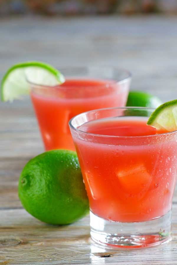 Two red cocktails with limes on the rims