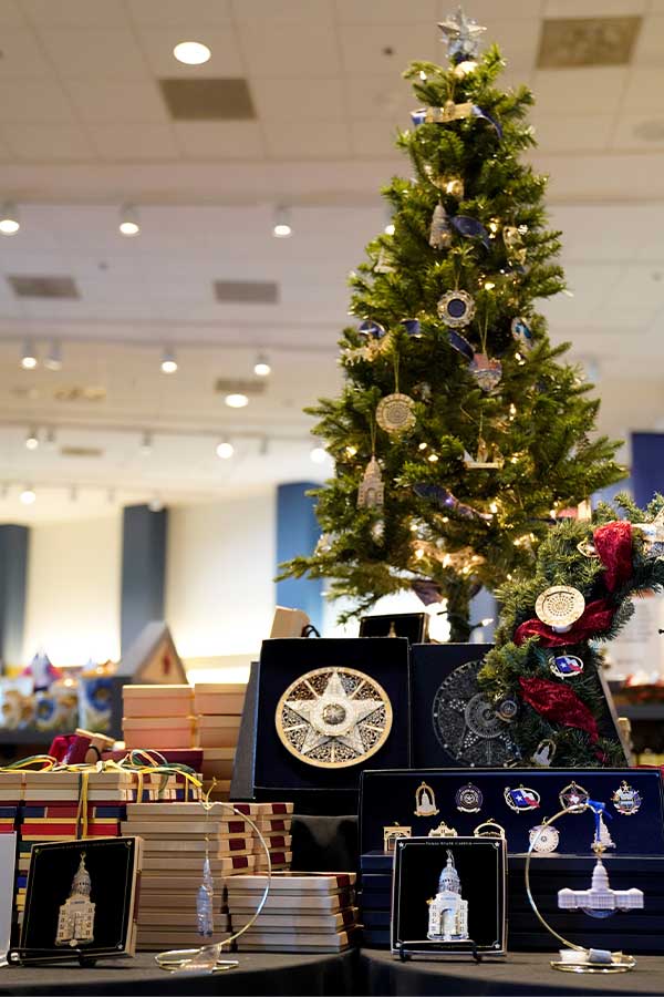 a small Christmas tree decorated with ornaments, at the foot of the tree are packaged ornaments for sale