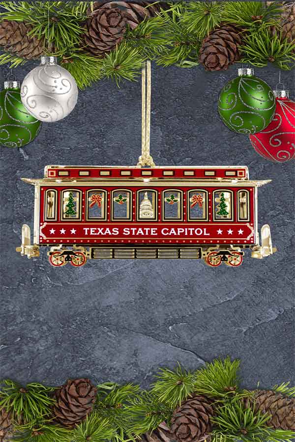 an ornament of a red and gold trolley on a gray background with garland above and below