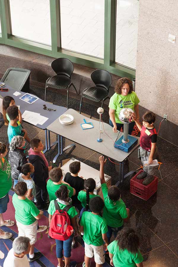 a group of kids wearing green shirts standing around a table in the Bullock Museum