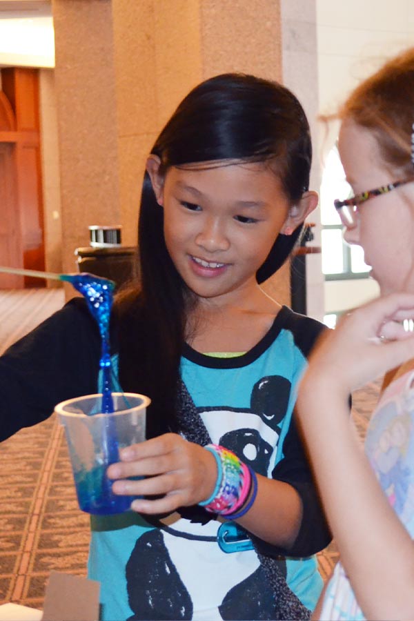 a student holding a cup of blue goop at Science Thursday at the Bullock Museum