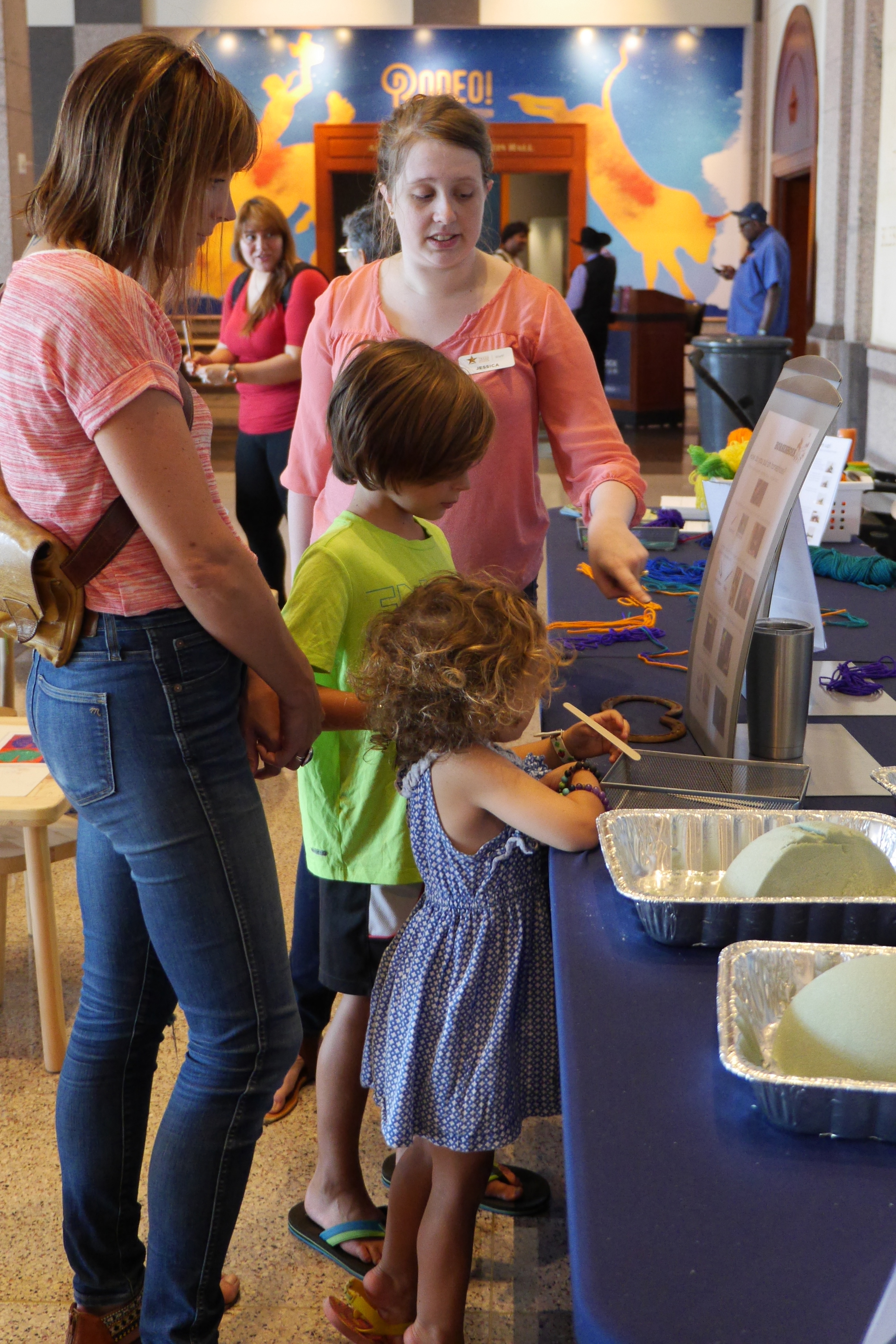 A girl stands to look at activities on a table