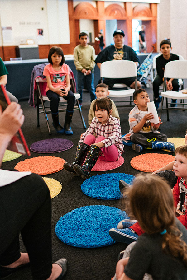 Children sitting on circular rugs at an activity 