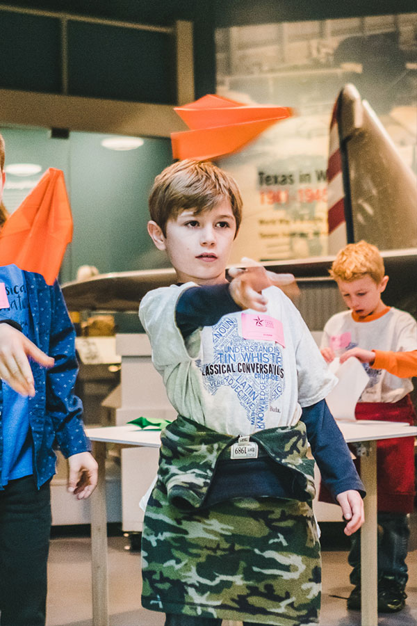 A boy throws a paper airplane