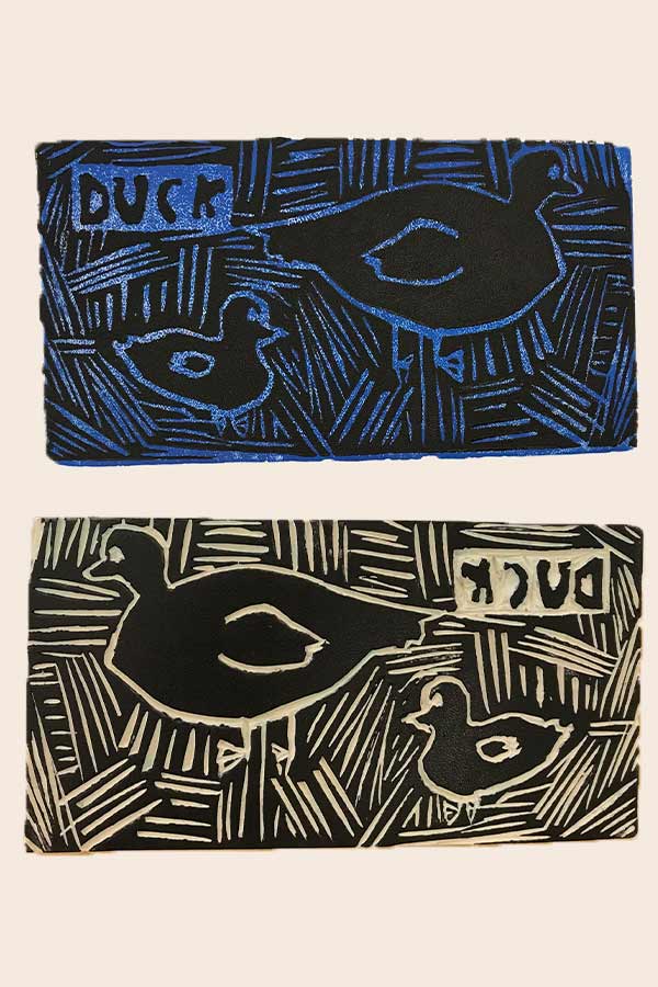a blue linoleum print of a duck in the water