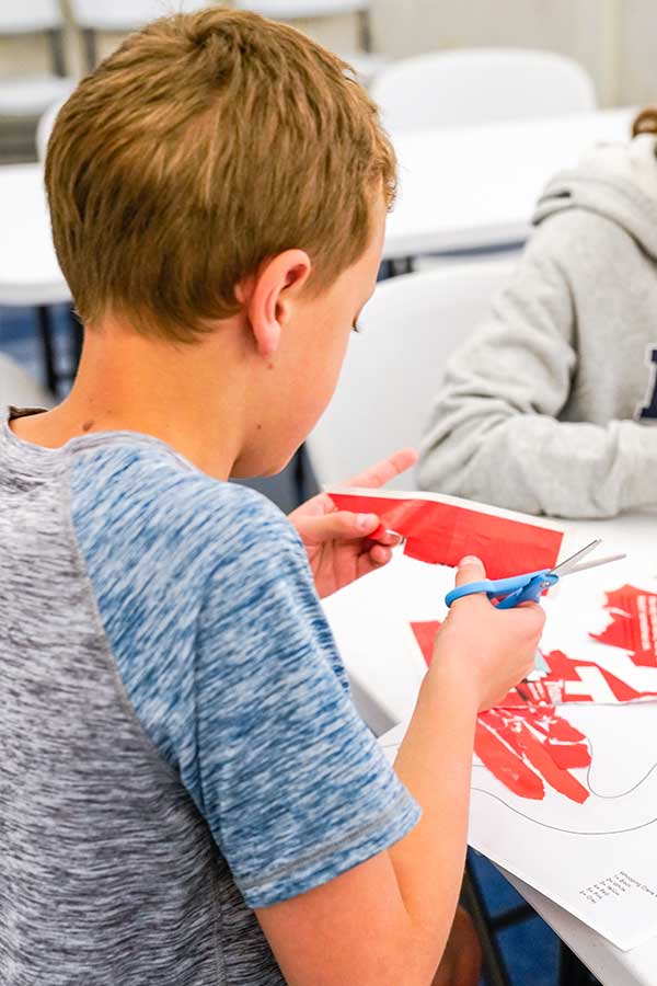 boy cutting a red sheet of paper at the Bullock Museum