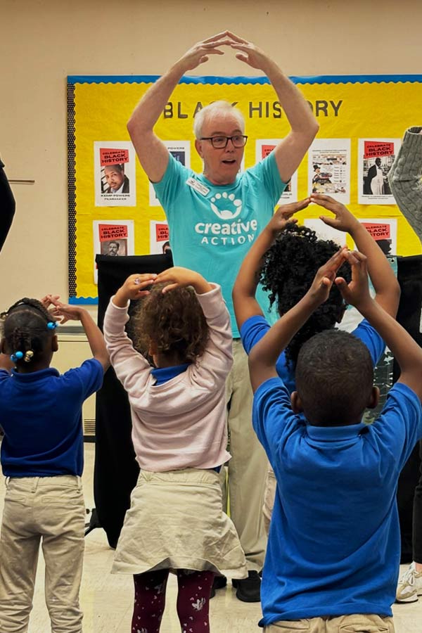 musician Mr. Freddy performing in front of dancing children in a classroom 